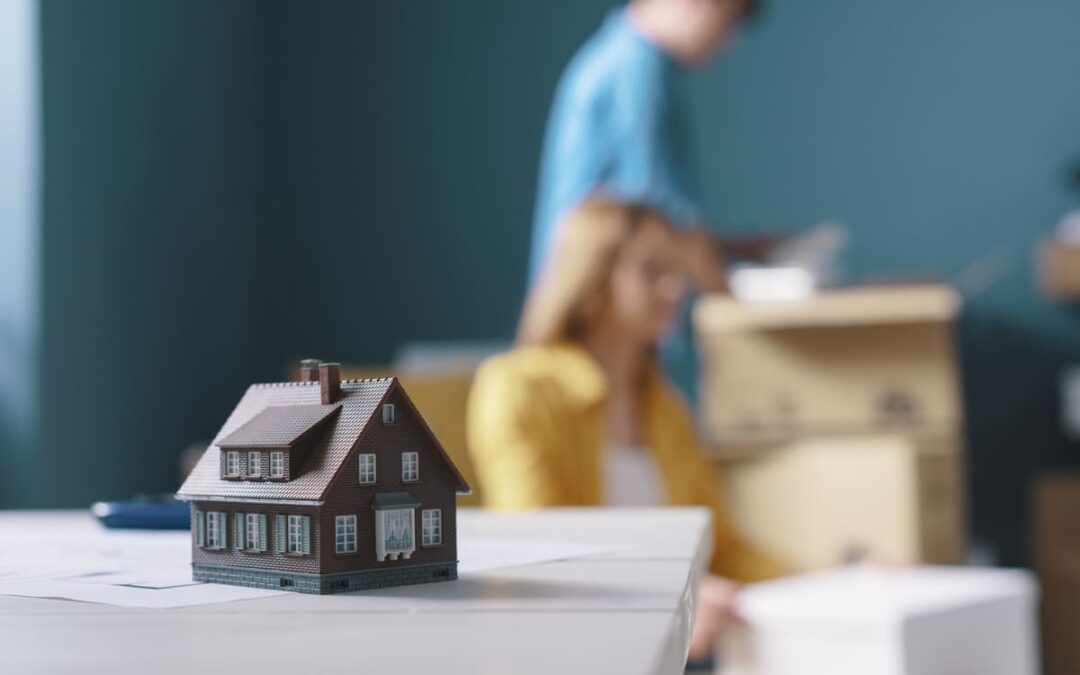 people packing boxes in background of home model on a table