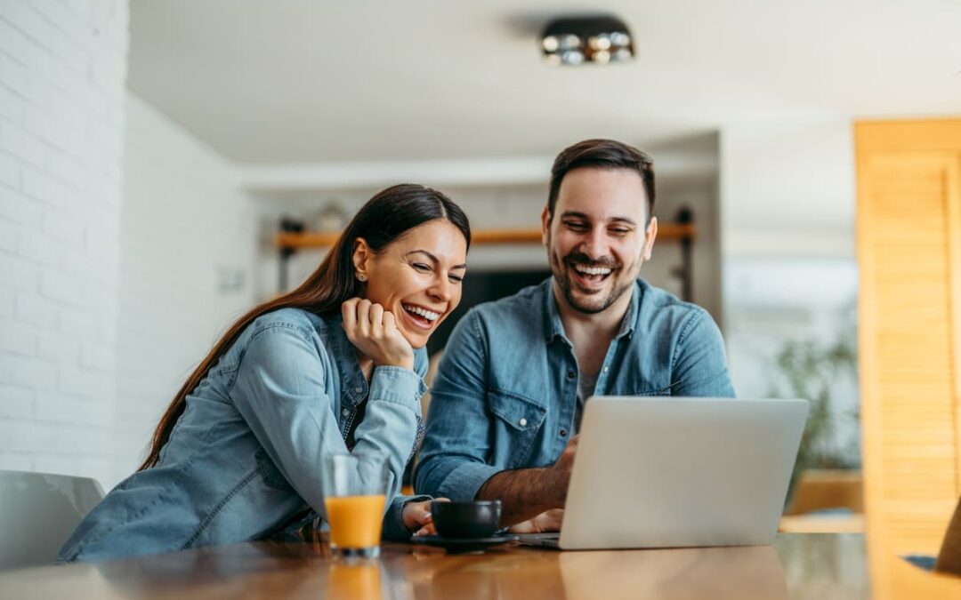 couple happily looking at laptop together