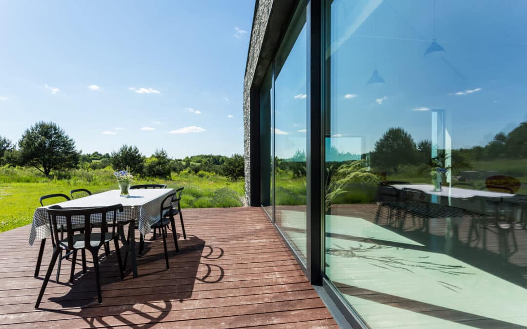 house deck with table and chairs overlooking green field